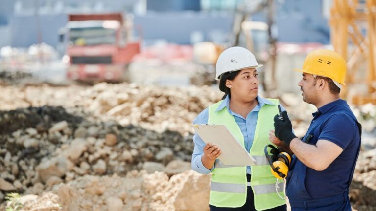 Zwei Fachkräfte mit Helm besprechen sich auf der Baustelle
