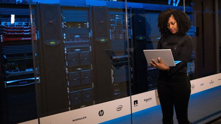 Technikerin mit Laptop vor Serverschränken